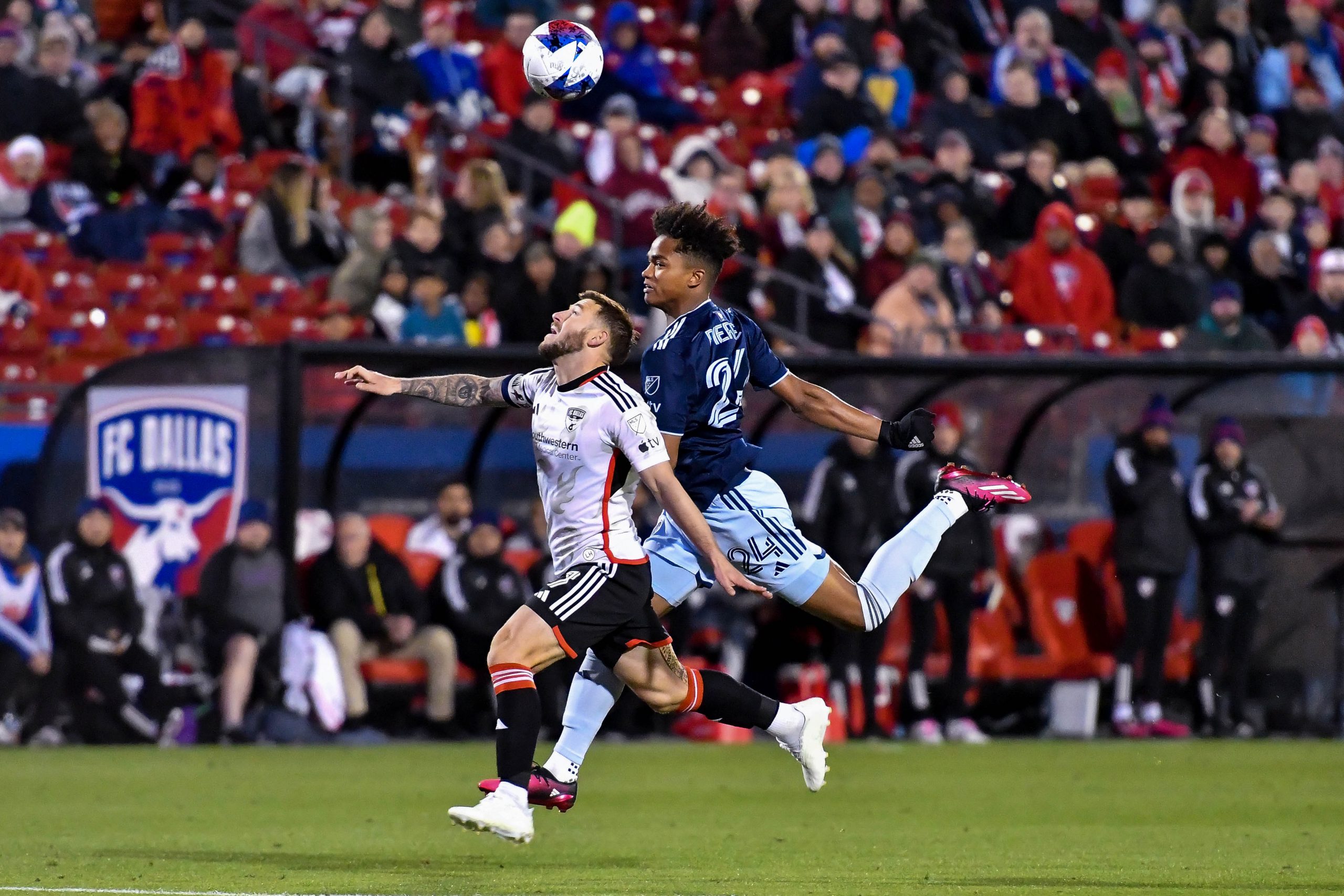 Paul Arriola runs underneath a ball headed by Sporting KC defender Kayden Pierre in the MLS match on Saturday, March 18, 2023, at Toyota Stadium. (Daniel McCullough, 3rd Degree)